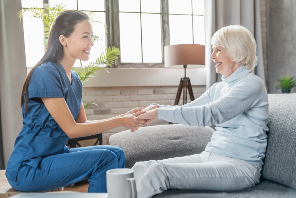 Caregiver holding hands with an older woman during a home care visit in Fairfax, VA